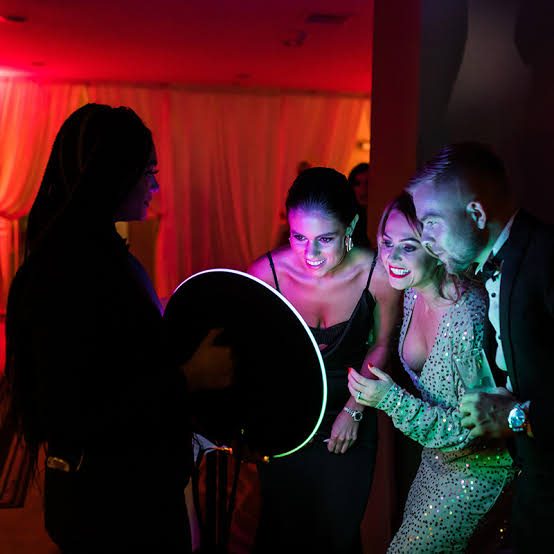 Guests posing with a ring-light booth at an evening party